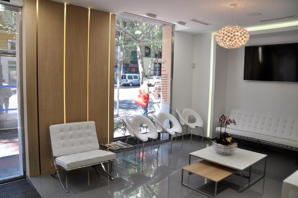 Sala de espera moderna en clínica dental diseñada con iluminación cálida y acabados de madera.