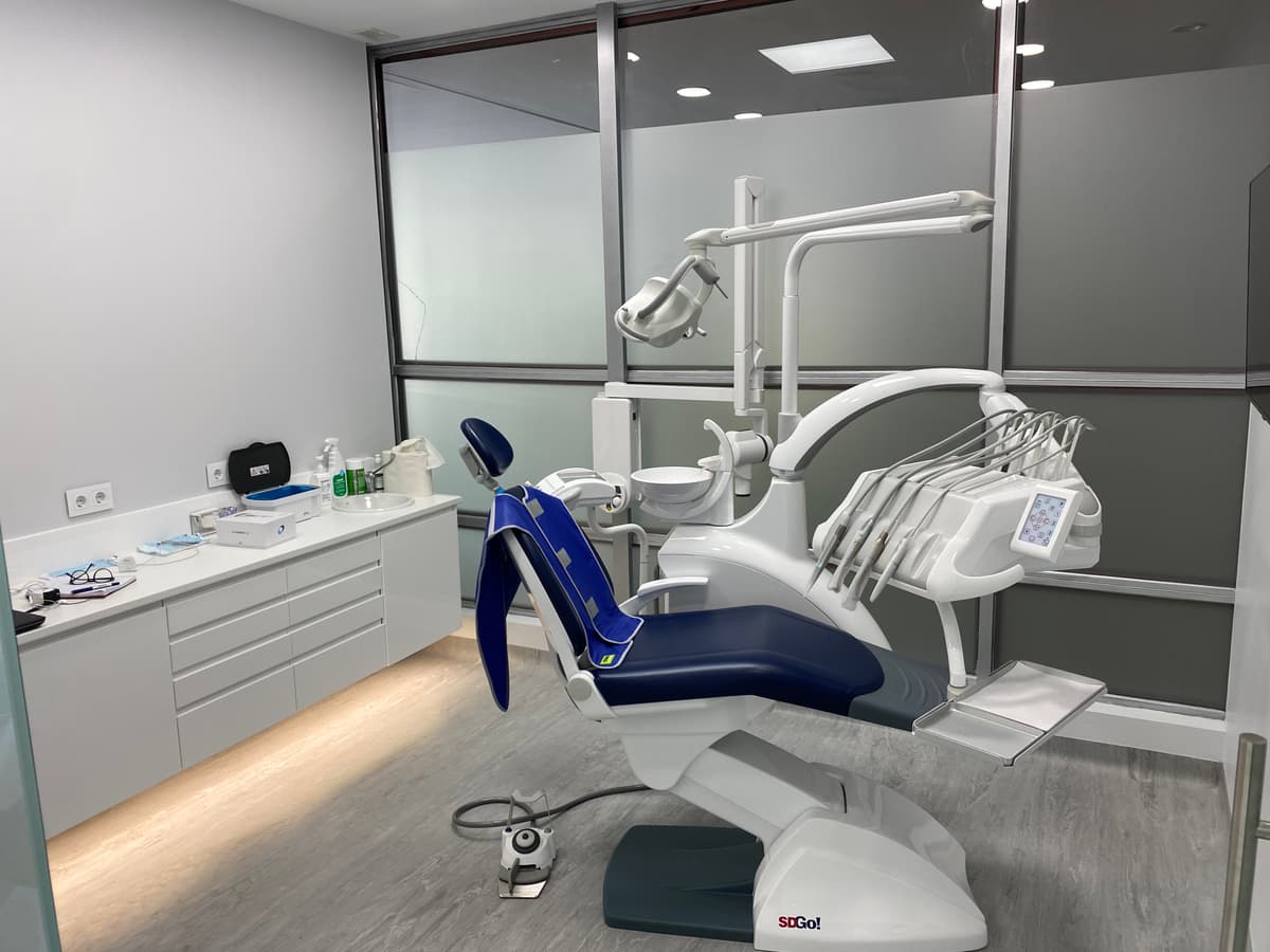 Sala de espera en clínica dental con iluminación natural y mobiliario cómodo en tonos claros.