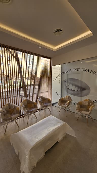 Sala de espera de una clínica dental en Madrid con sillas modernas, decoración minimalista y un ventanal con mensaje motivador sobre sonrisas.